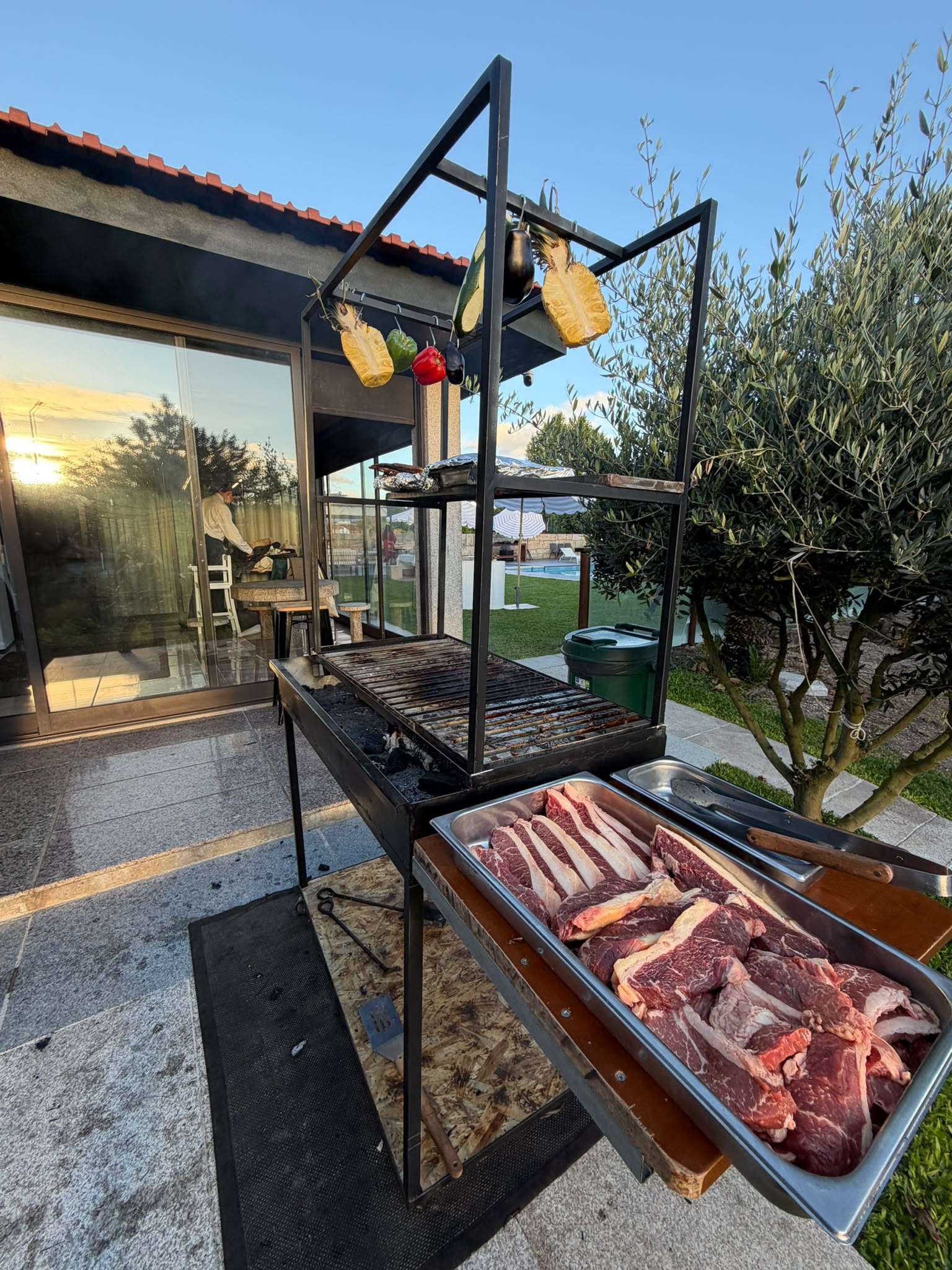 Parrilla com carnes cruas marinadas prontas para grelhar ao pôr do sol numa esplanada moderna