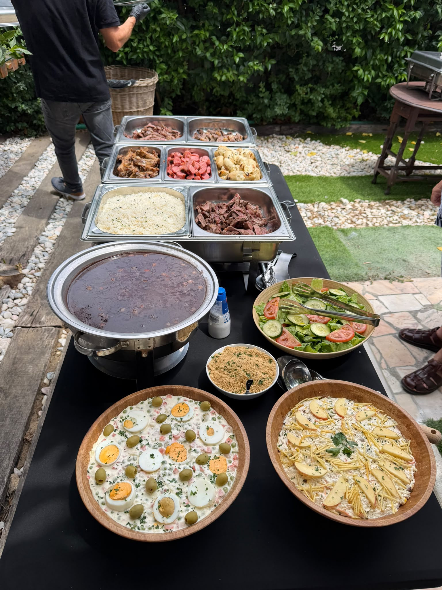 Buffet completo de catering brasileiro com carnes grelhadas, farofa, saladas e acompanhamentos ao ar livre