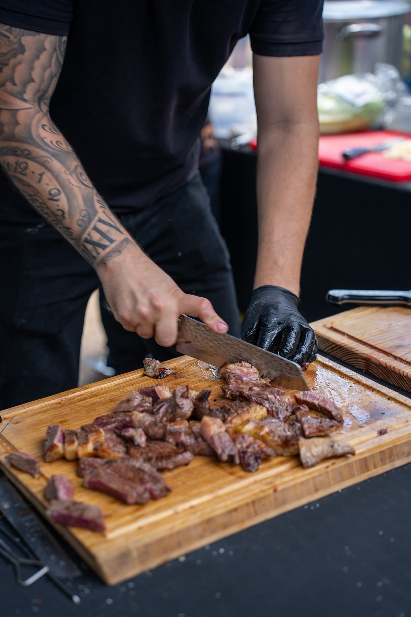 Churrasqueiro a fatiar bife suculento na tábua em evento de catering ao ar livre